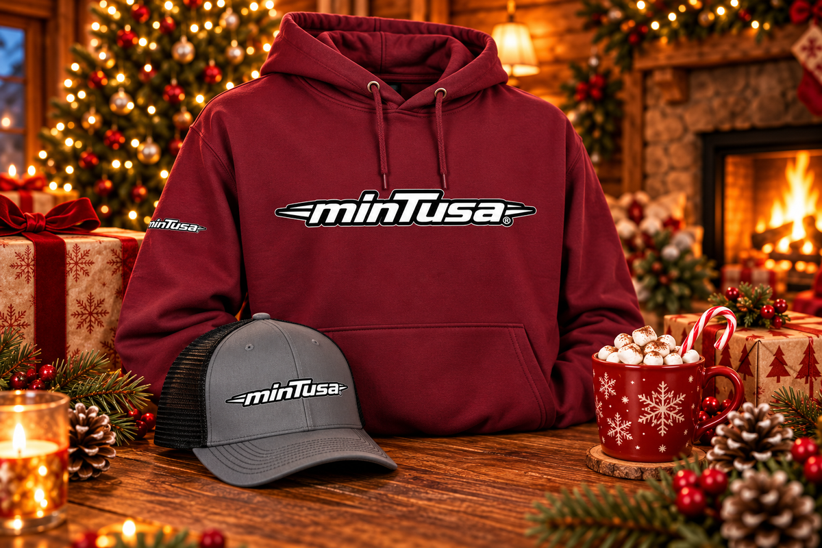 minTusa Classic Gift Set: a maroon hoodie and a charcoal and black embroidered trucker cap with the minTusa logo by a Christmas tree and fireplace