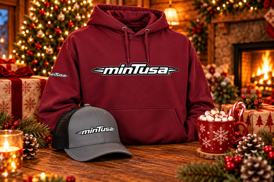 minTusa Classic Gift Set: a maroon hoodie and a charcoal and black embroidered trucker cap with the minTusa logo by a Christmas tree and fireplace