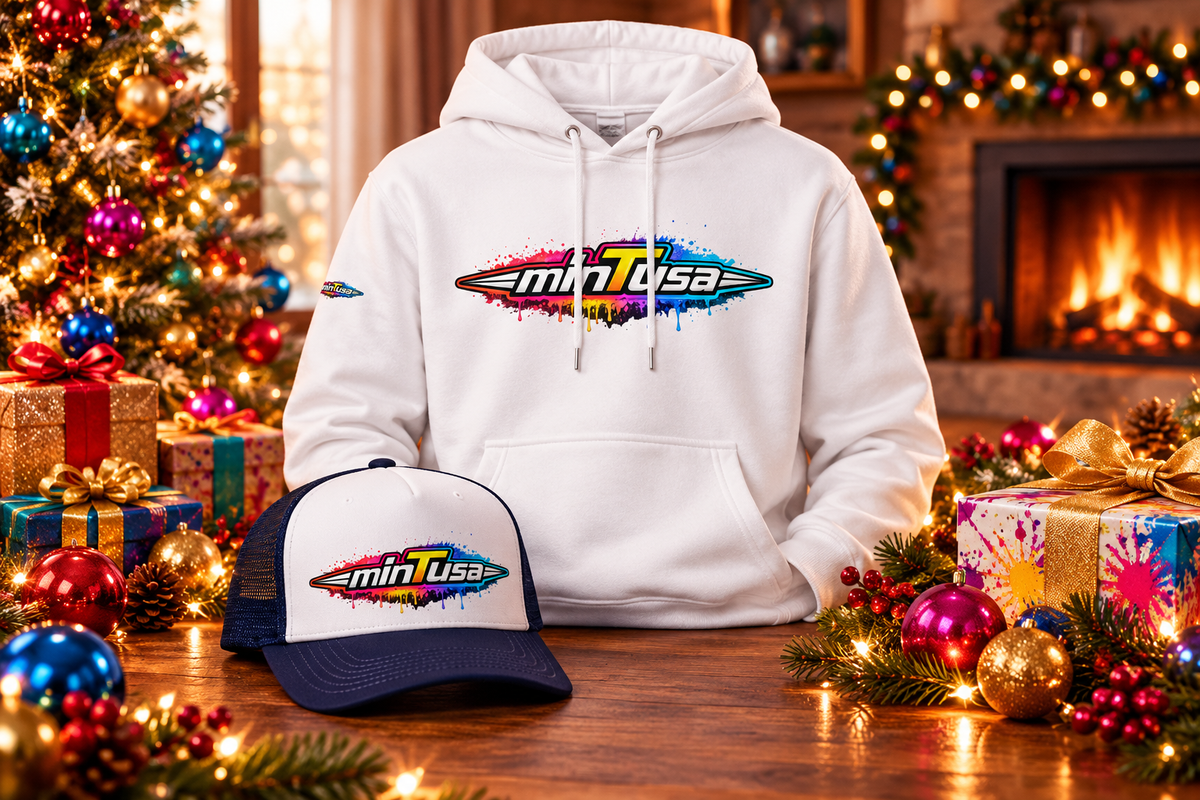 minTusa Splash Gift Set: a white hoodie and a navy and white foam trucker hat, both with the colorful paint-splash minTusa logo, among festive ornaments, gift boxes and a fireplace